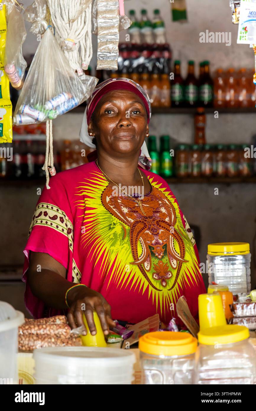 Portrait of a smiling woman shopkeeper in a headscarf and bright pink ...
