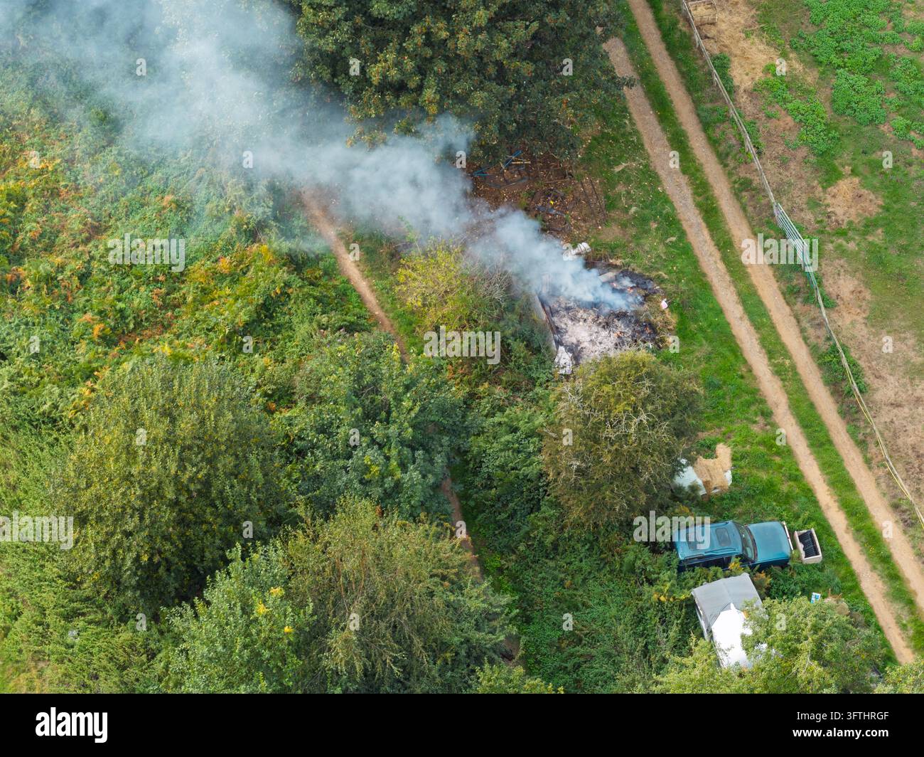 Aerial view of a small fire burning in a rural field with rising smoke ...