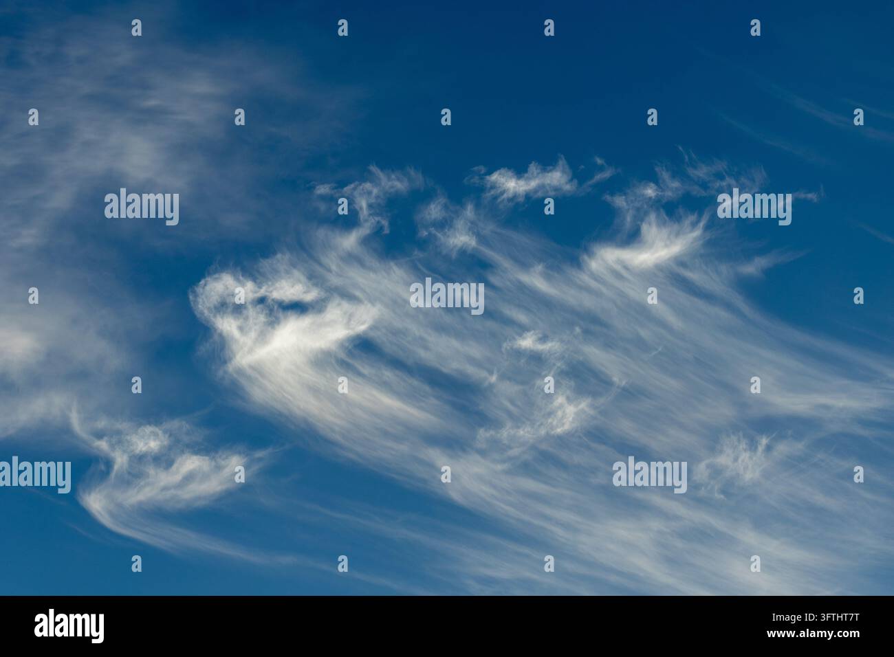 Delicate featherlike cirrus clouds spreading across a deep blue sky Stock Photo