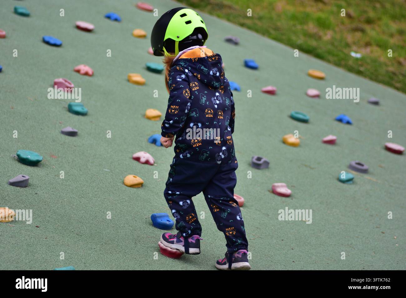 Young girl wearing a safety helmet walking across a colorful outdoor ...