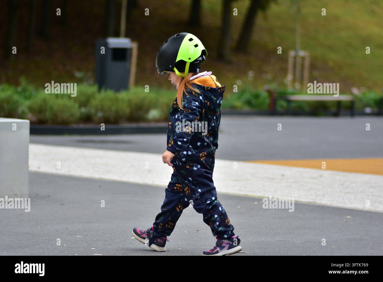 Young girl wearing a bright safety helmet walking through a modern ...