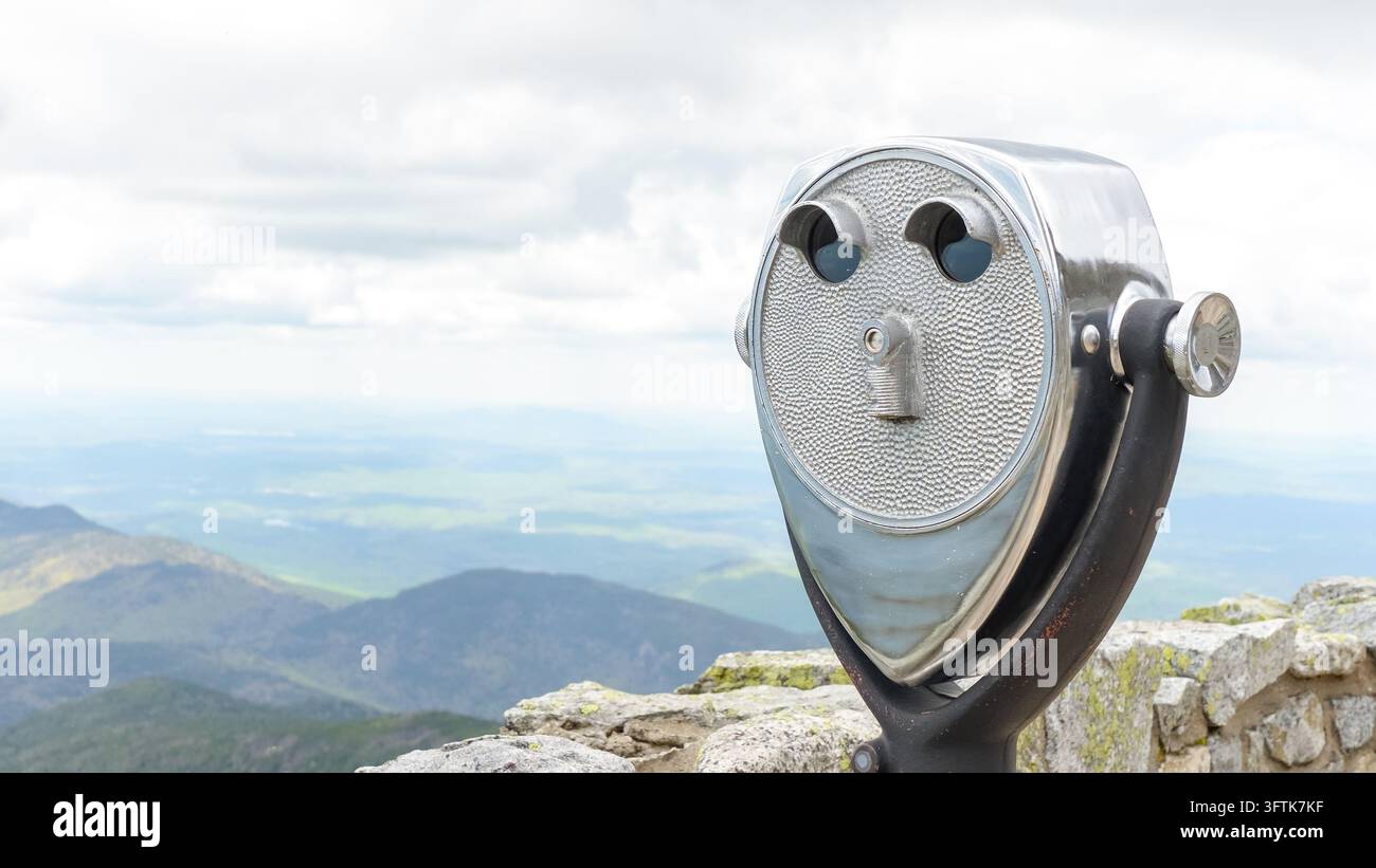 A coin operated viewing telescope stands on a rocky summit, facing ...