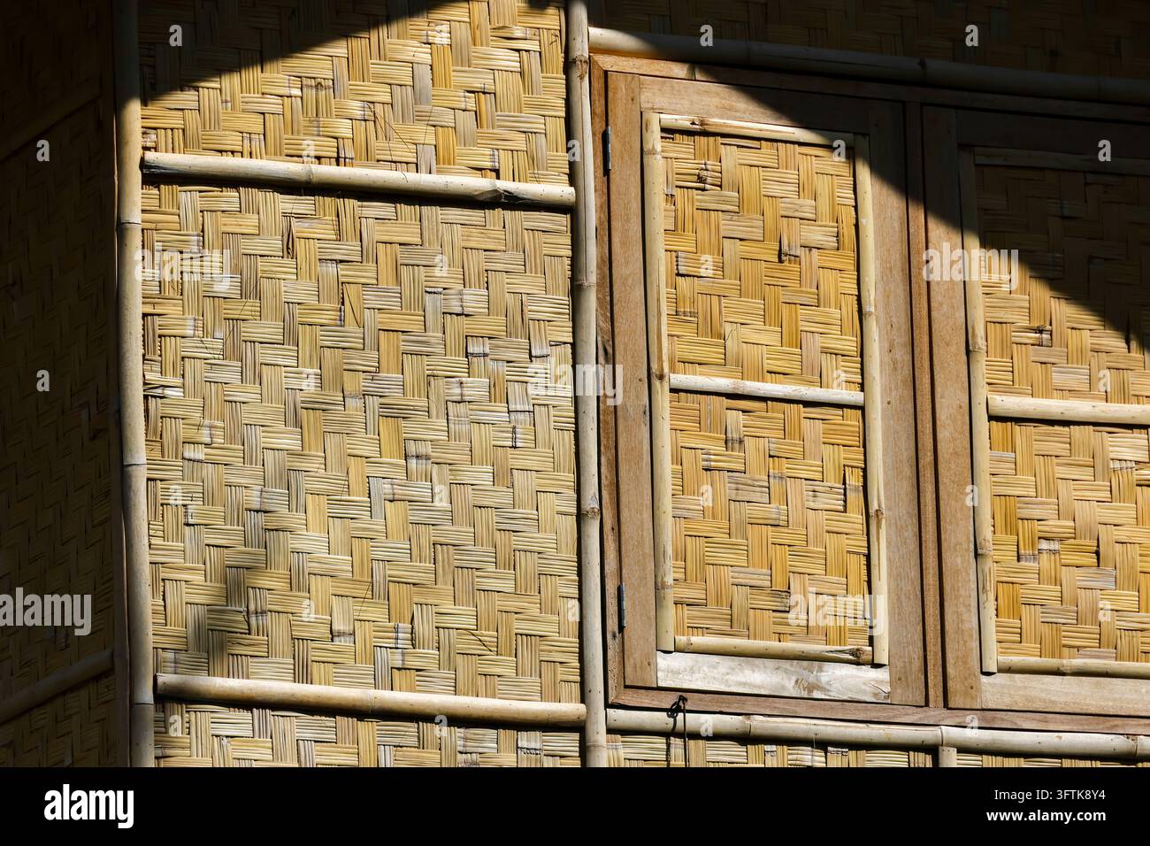 A bamboo wall panel with woven texture, wooden frame, and warm sunlight ...