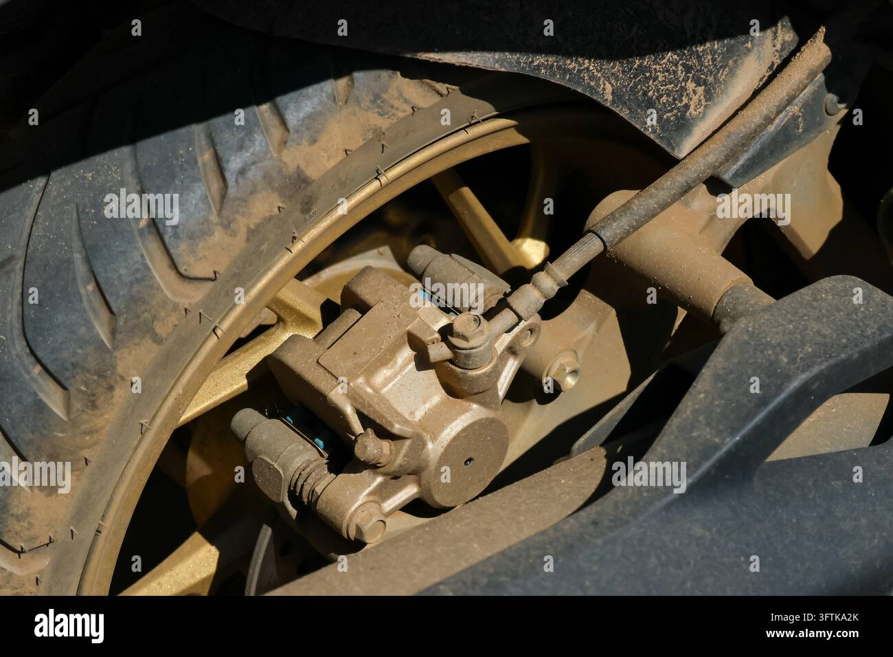 A closeup of dusty rear wheel brake assembly, tire tread, suspension ...