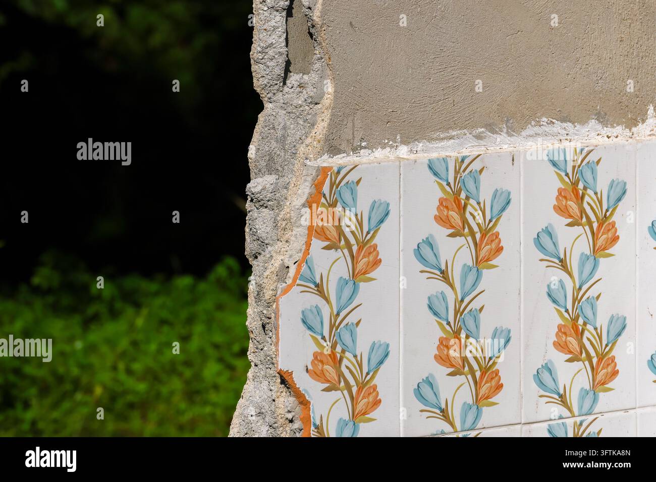 A cracked plaster wall with colorful floral tile pattern beside ...