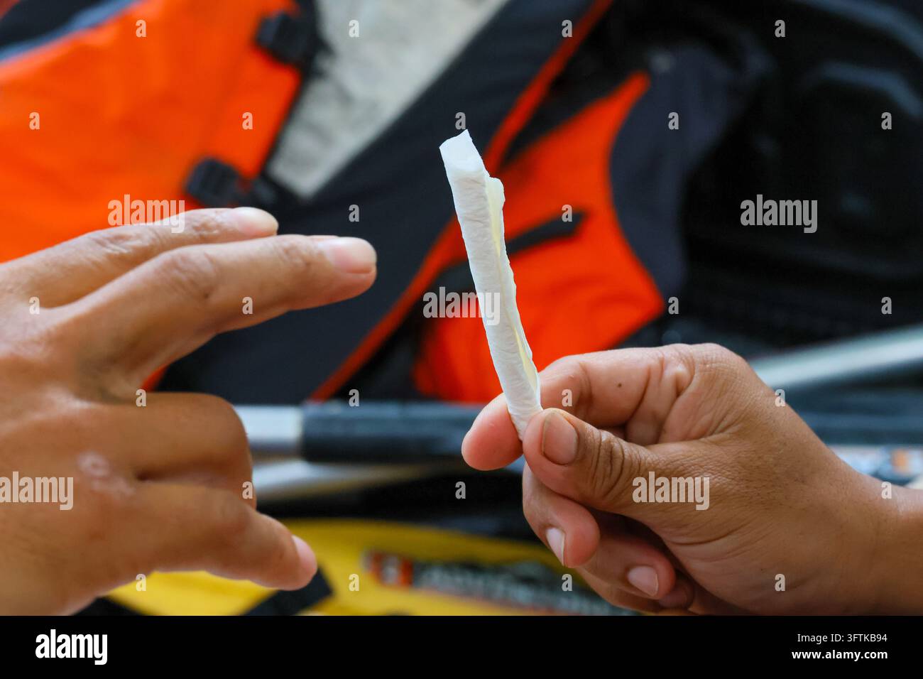 A hand holding rolled paper beside pointing hand, outdoor trade setting ...