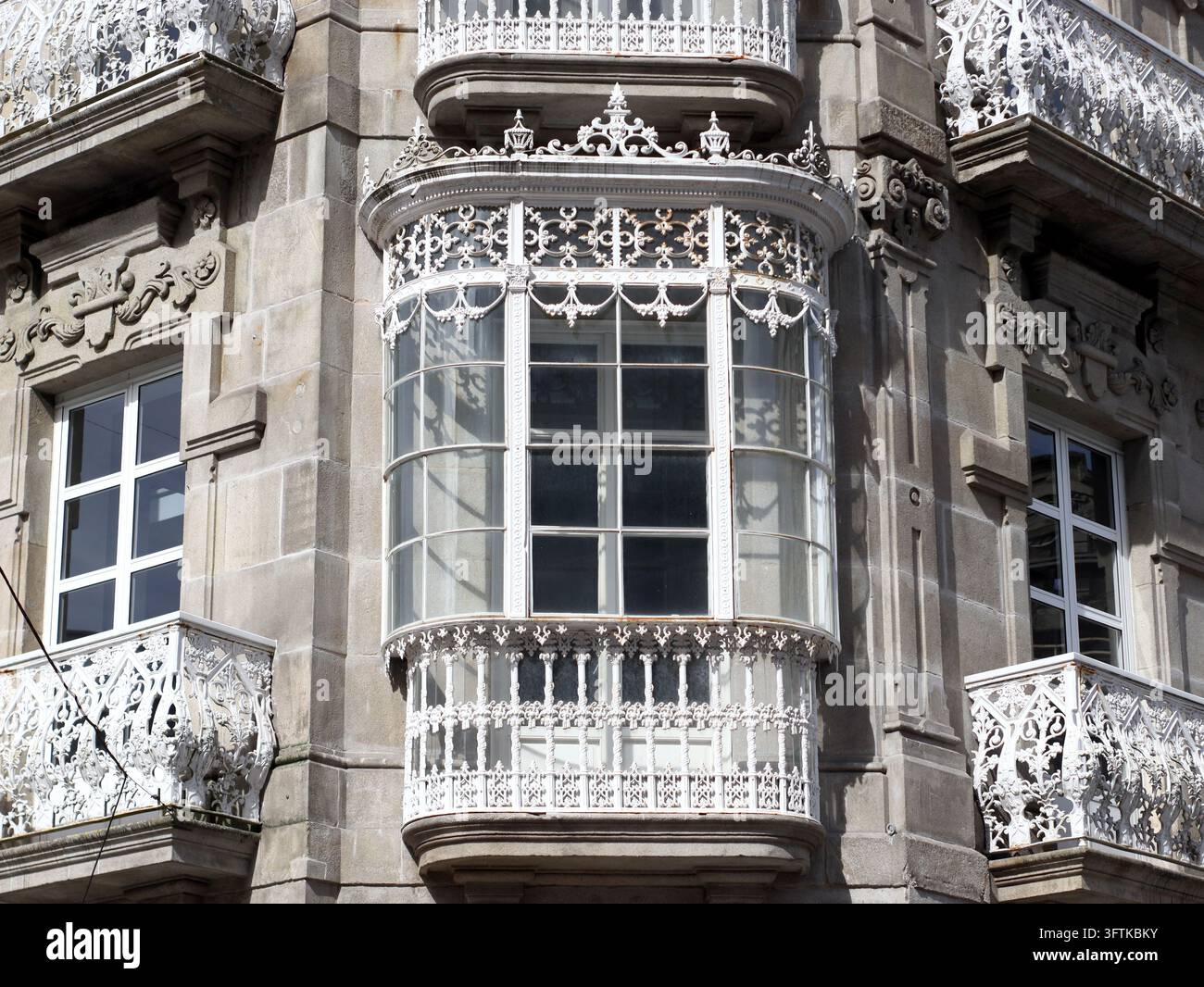 Ornate stone building facade with white wrought iron balconies and a ...