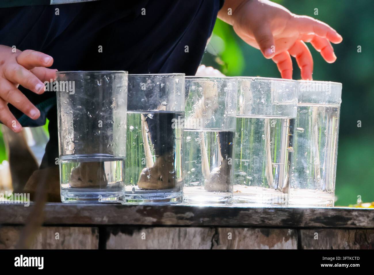 A transparent glass with water arranged on wooden table during outdoor ...