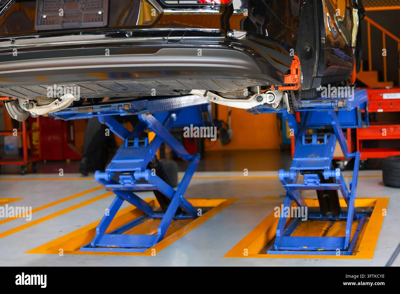 A vehicle undercarriage elevated on blue hydraulic lift in organized ...