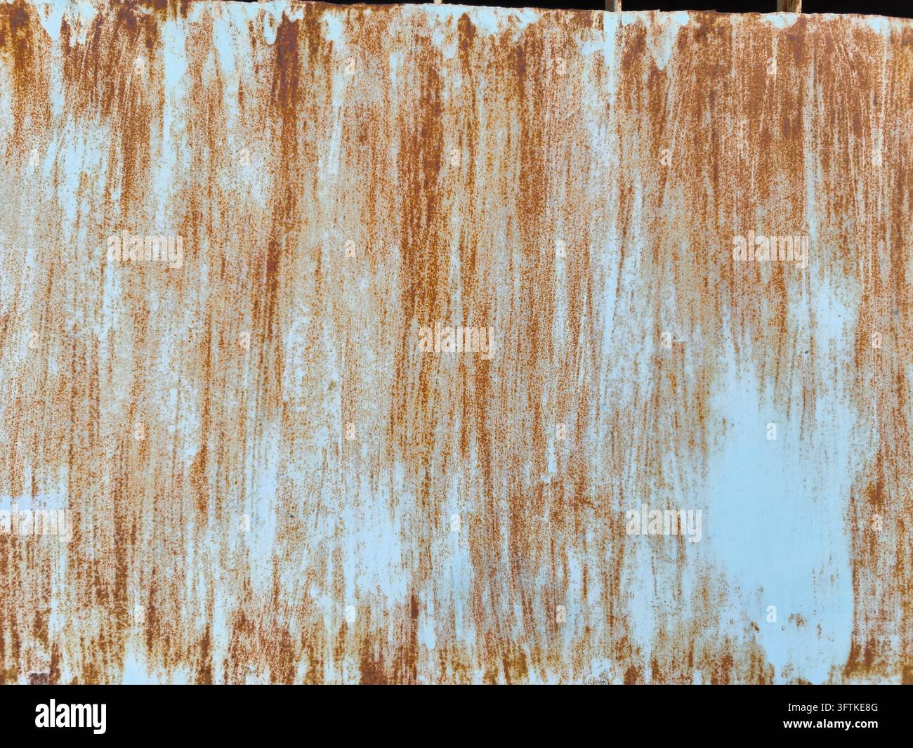 Weathered blue painted metal surface covered with dense vertical rust ...