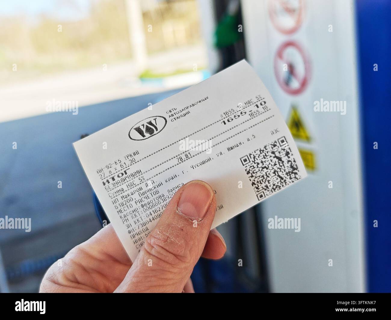 Perm, Russia - May 4, 2026: Hand holds a small printed gasoline receipt ...