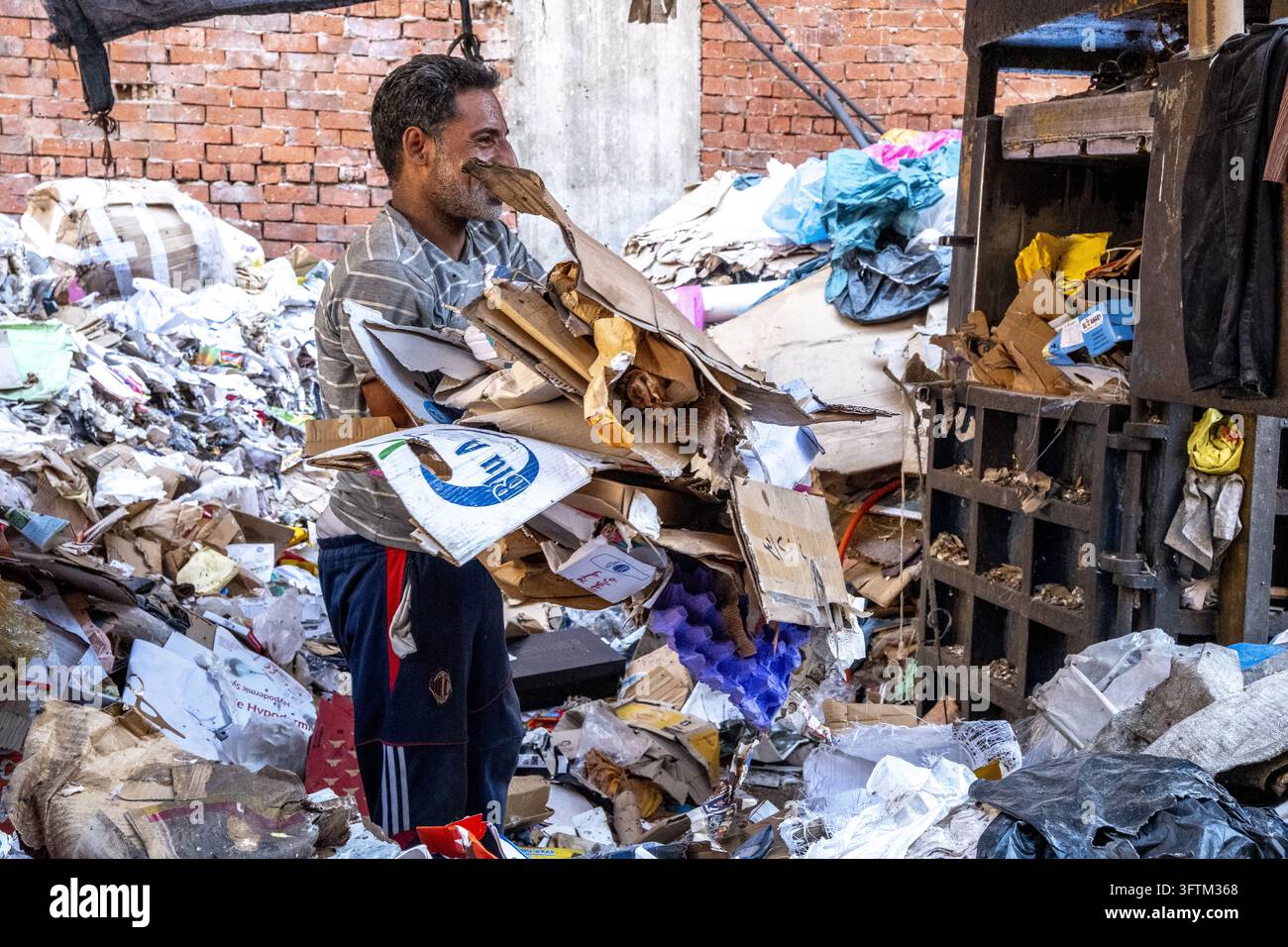 A worker carries a stack of cardboard in the Moqattam ragpickers ...
