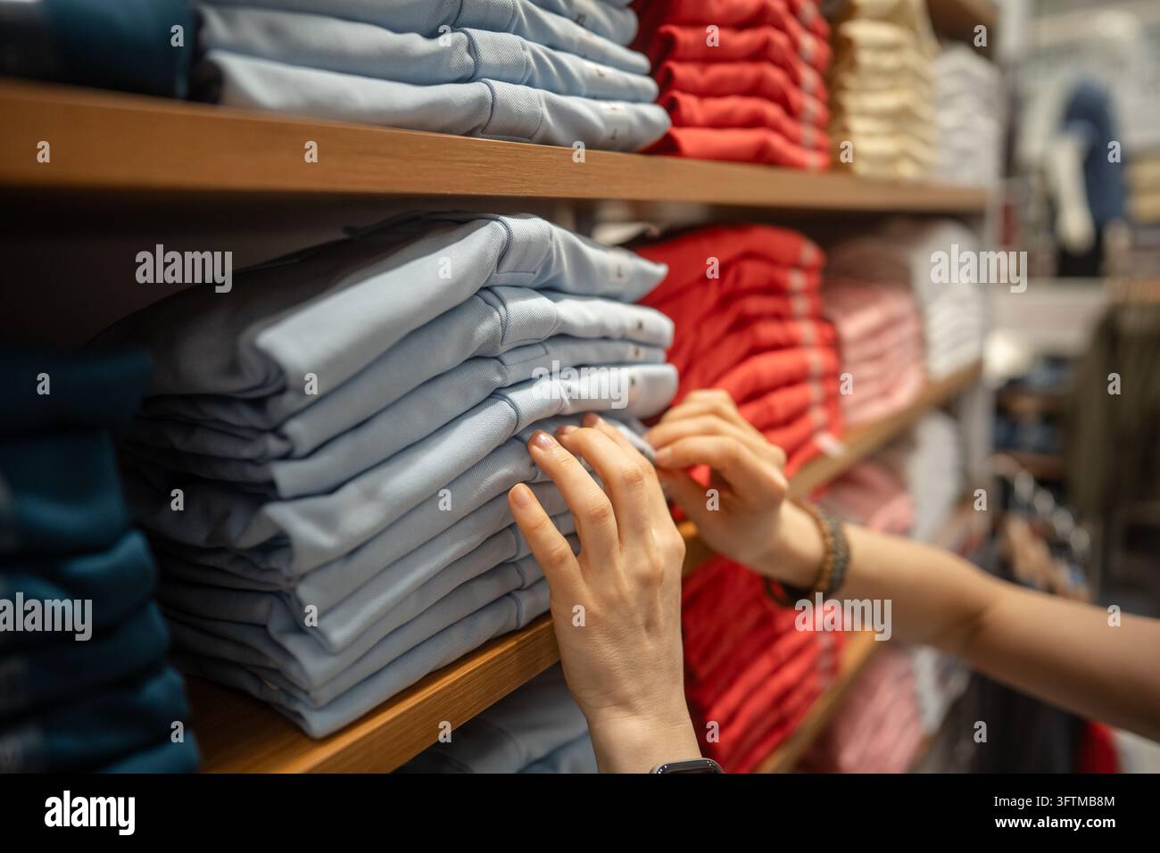 Female purchasing basic clothing at fashion shop, looking through stack ...