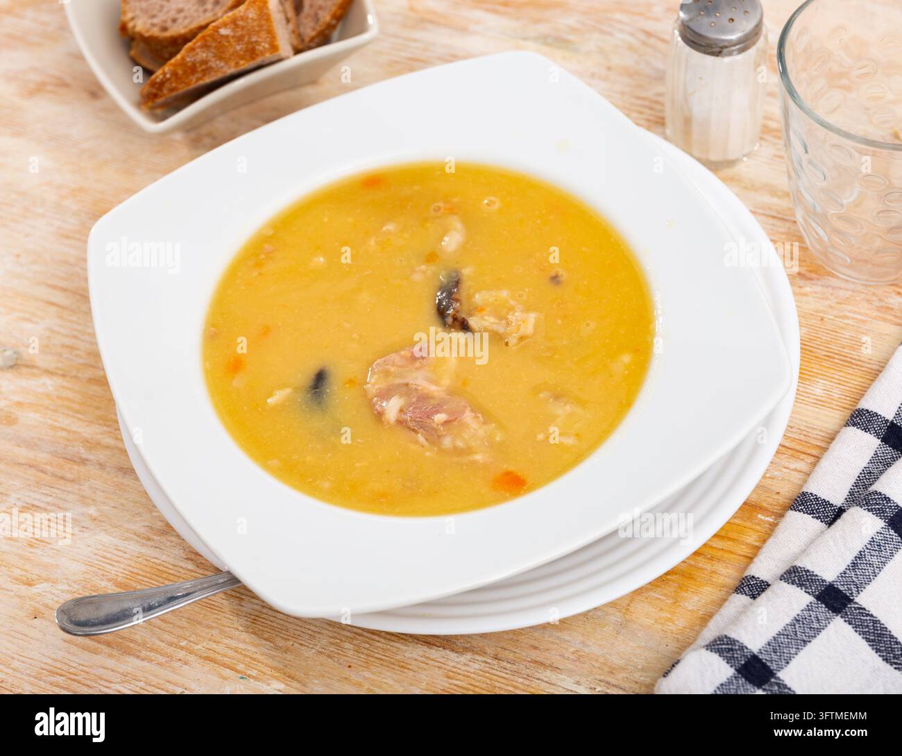 Appetizing hot pea soup with smoked meats served with slices of bread ...