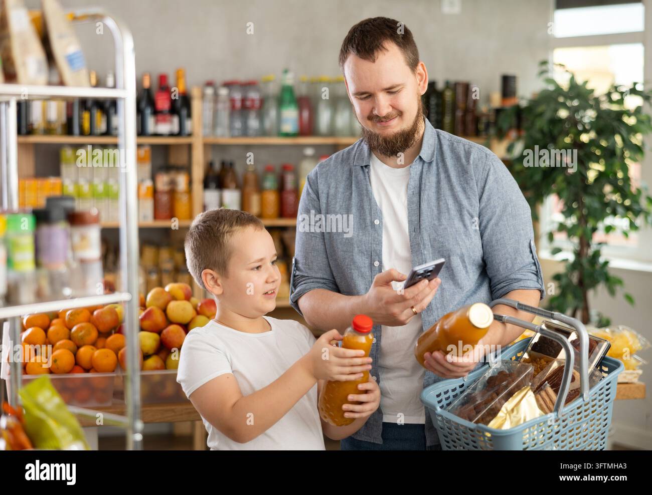 Man Using Software Young bearded man with tween son buying organic bottled juices in ...