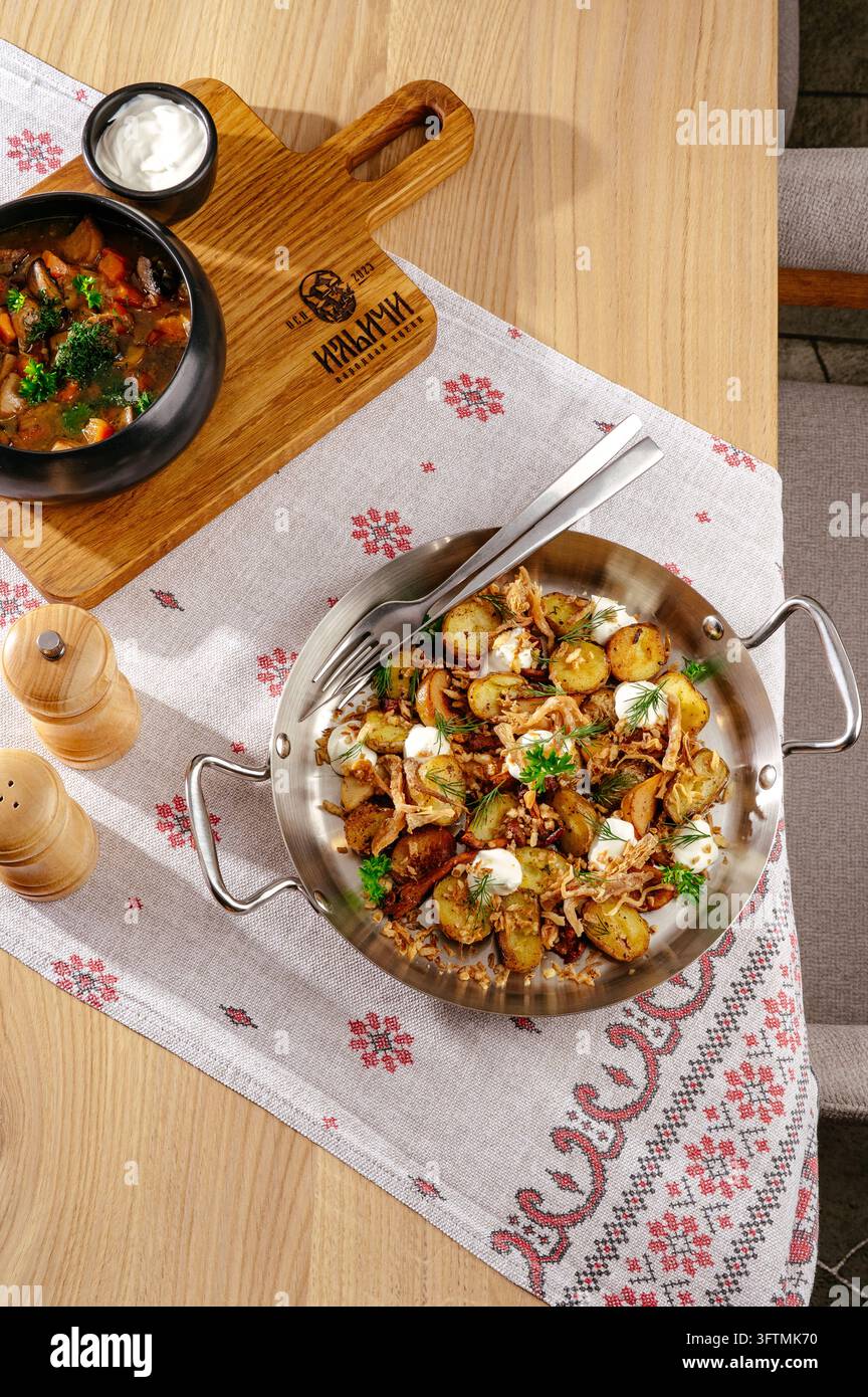 Traditional roasted potato dish and mushroom soup on a table Stock Photo