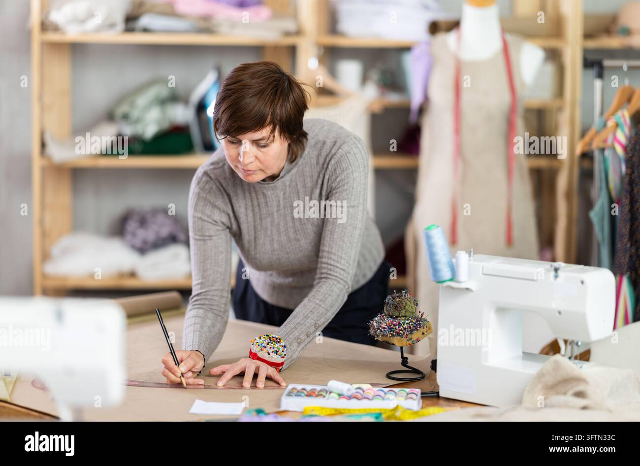 Woman tailor draw dress pattern of product on paper and participate in ...