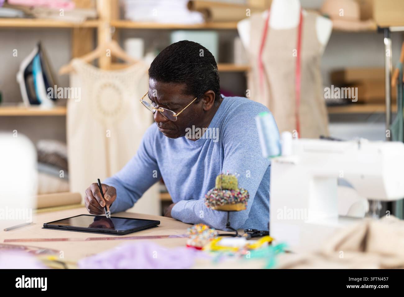 African American man tailor creates sketch of dress on tablet Stock ...