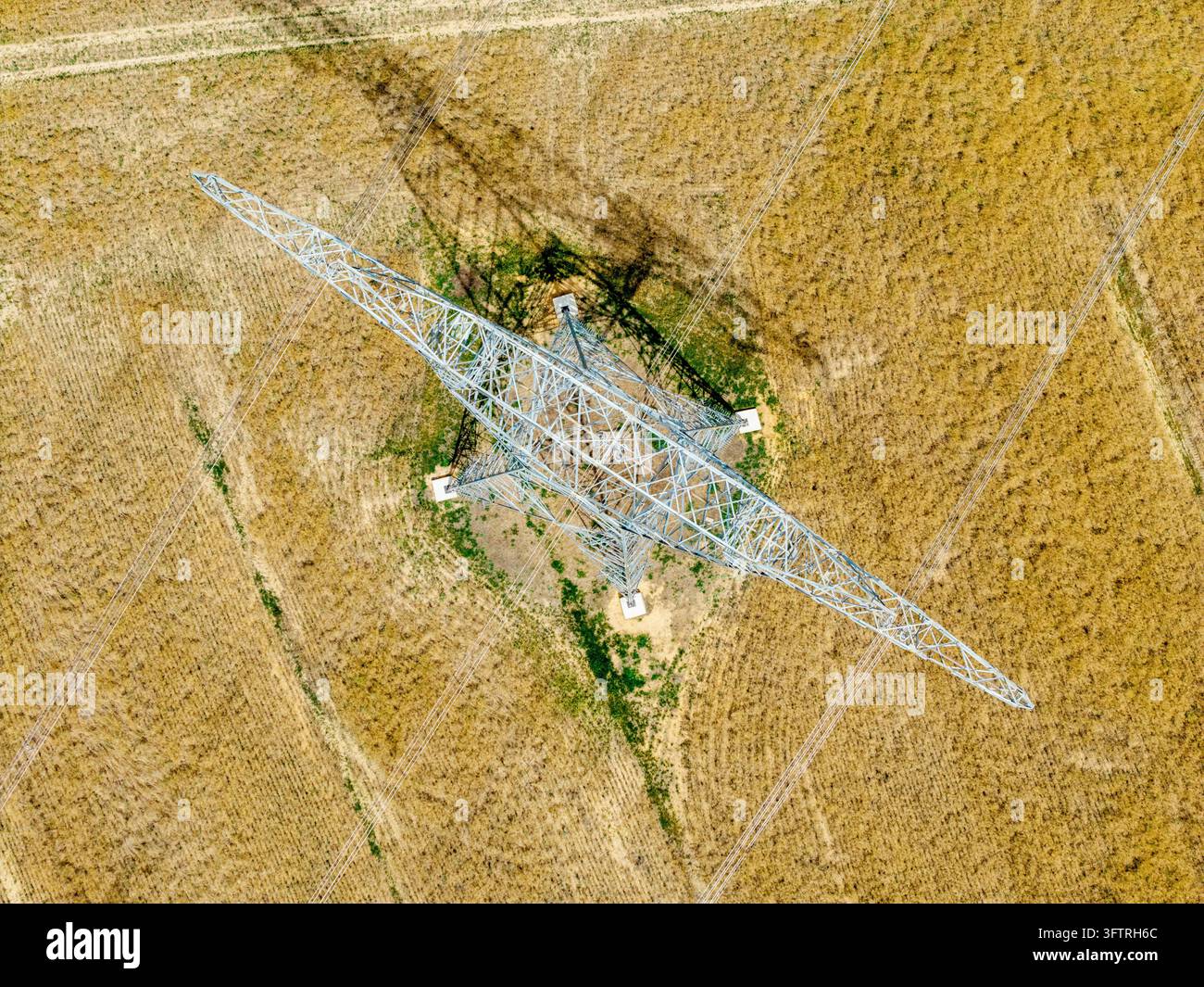 Aerial view of a metal electricity pylon standing in a dry, harvested ...