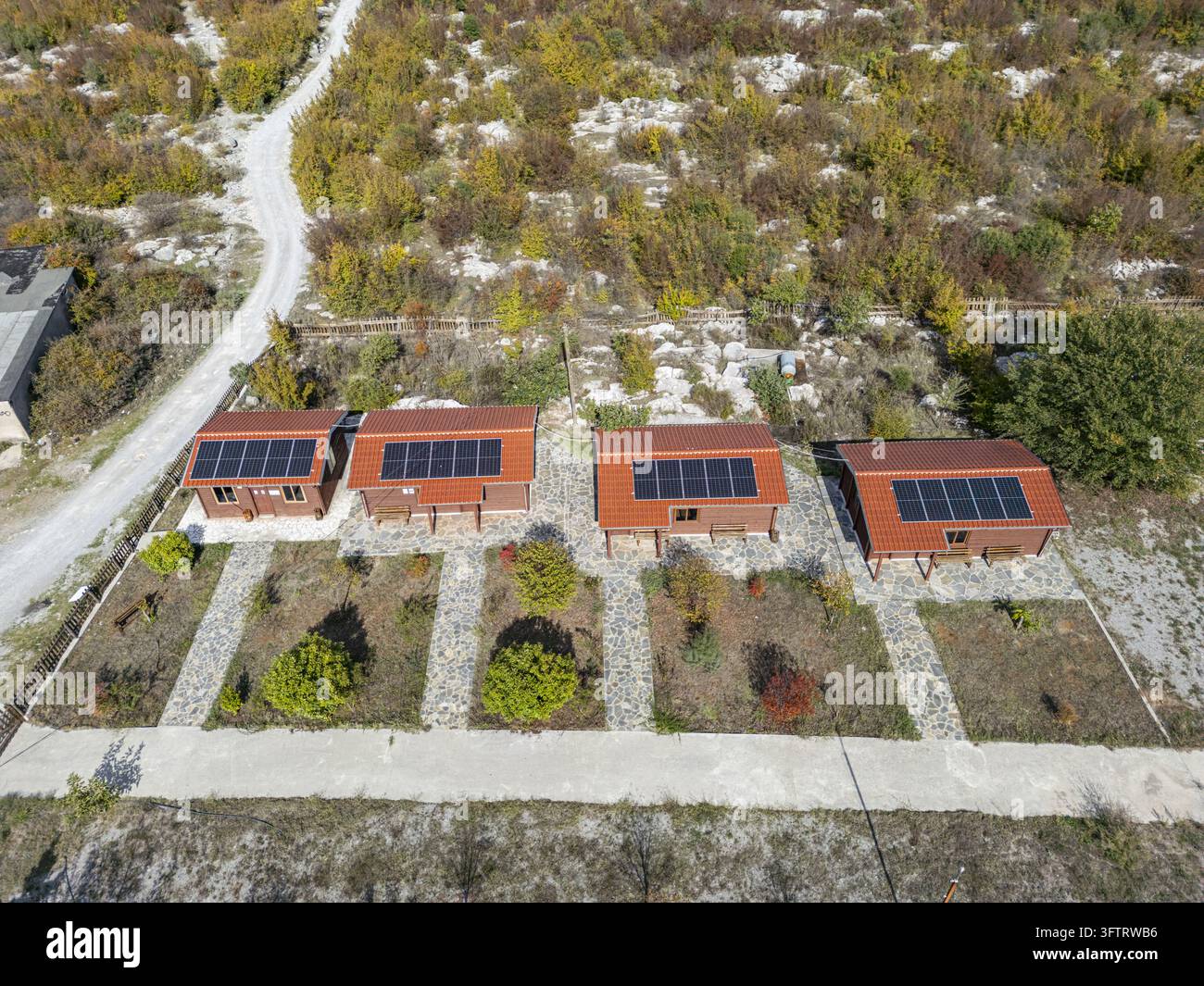 Aerial view of four small wooden cabins with red tiled roofs and solar ...