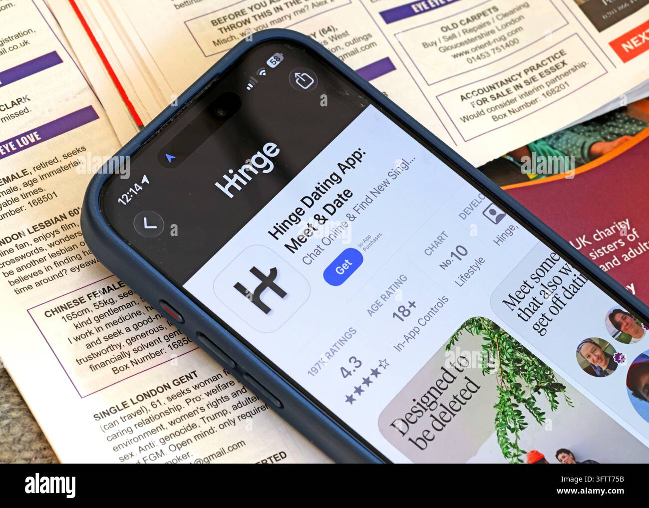 Hinge dating app profile and branding displayed on an Apple iPhone lying on printed pages. Stock Photo