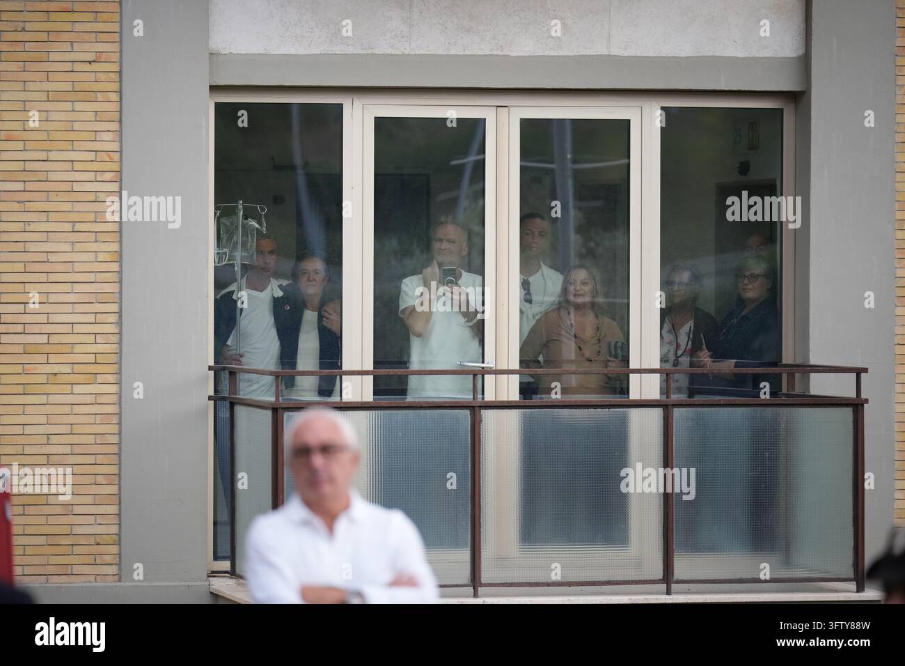 People crowd a window to watch Pope Leo XIV leaving Rome's Agostino ...