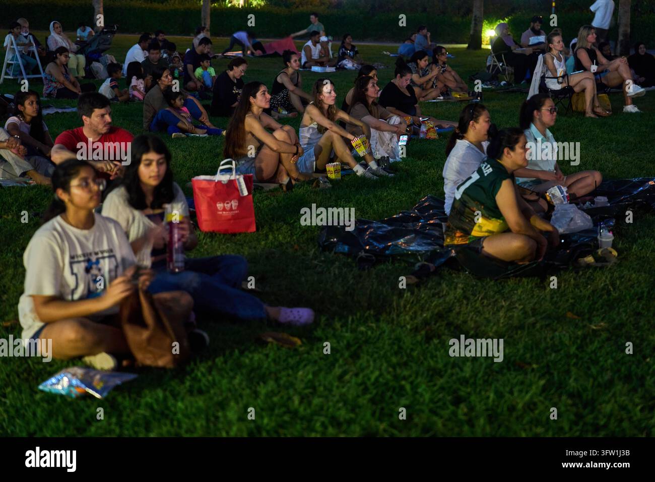 People sit on the grass as they watch an outdoor movie screening in ...