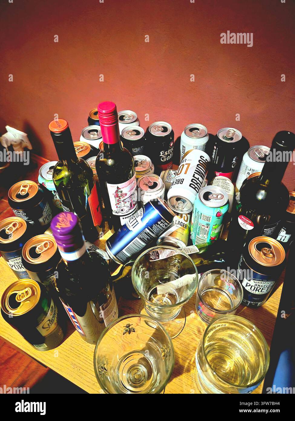 Table with empty alcohol containers including wine bottles and beer and cider cans after a party - Smartphone Captured Stock Image