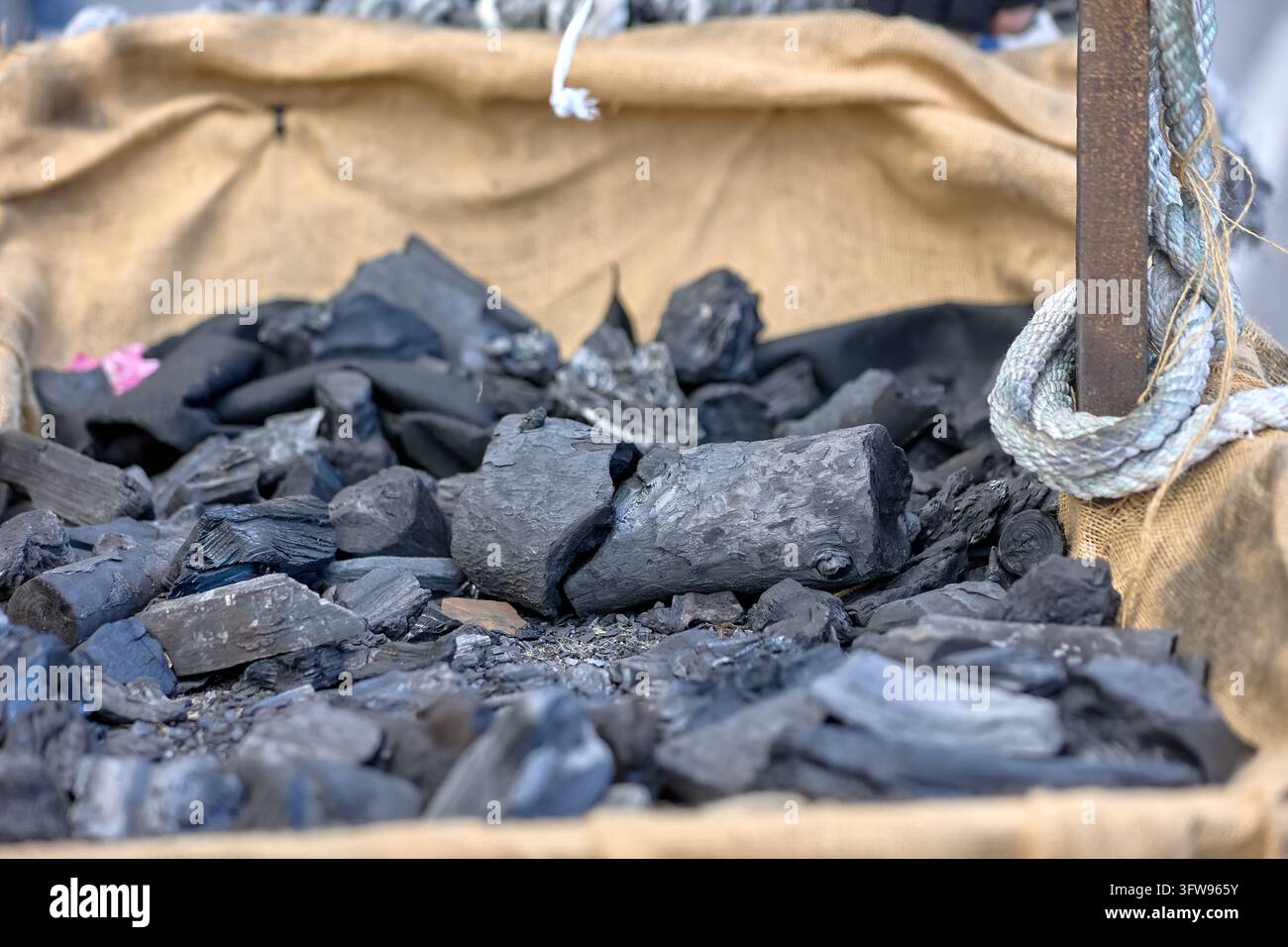 Close view of black coal pieces in a burlap lined parade cart with rope detail. Almunecar, Spain, January 6, 2026. Stock Photo