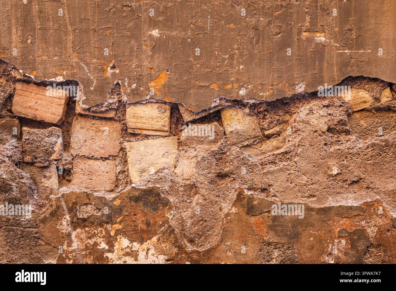 Old wall texture showing layers of damaged plaster and exposed bricks Stock Photo