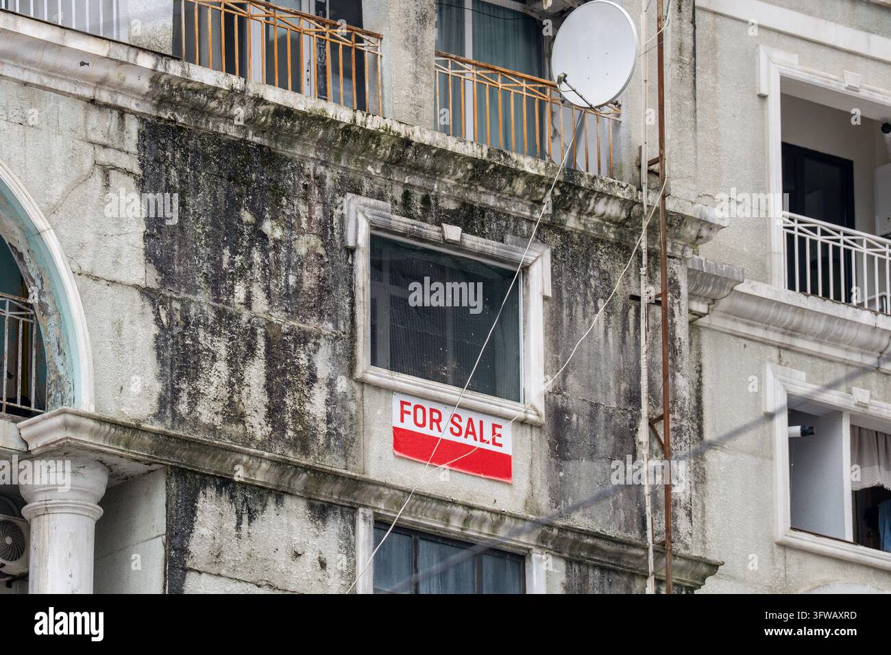 Heavily water-damaged residential building facade with red and white ...