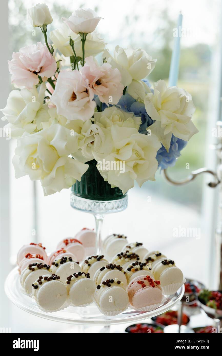 Macarons on a dessert stand with a floral arrangement featuring white ...