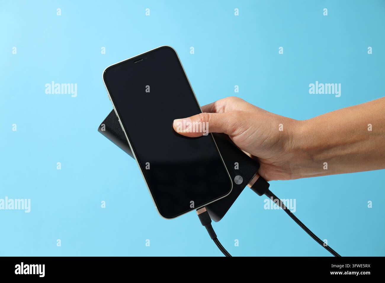 Powerbank and smartphone in hand on blue background Stock Photo