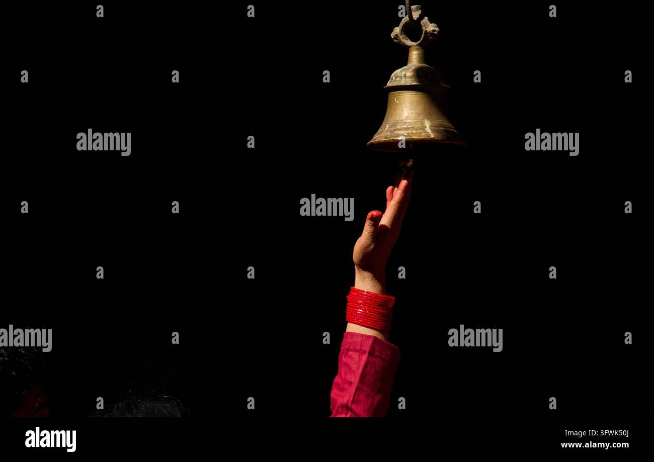 A devotee rings the bell hanging outside Naradevi Temple after offering ...