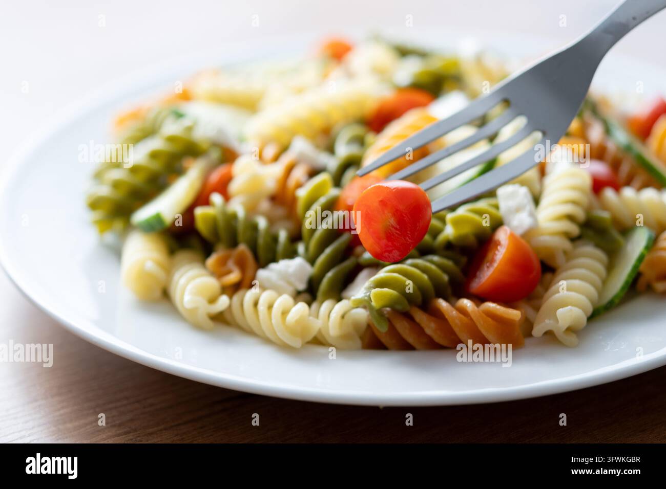 Colorful fusilli pasta salad with fresh vegetables and feta cheese on ...