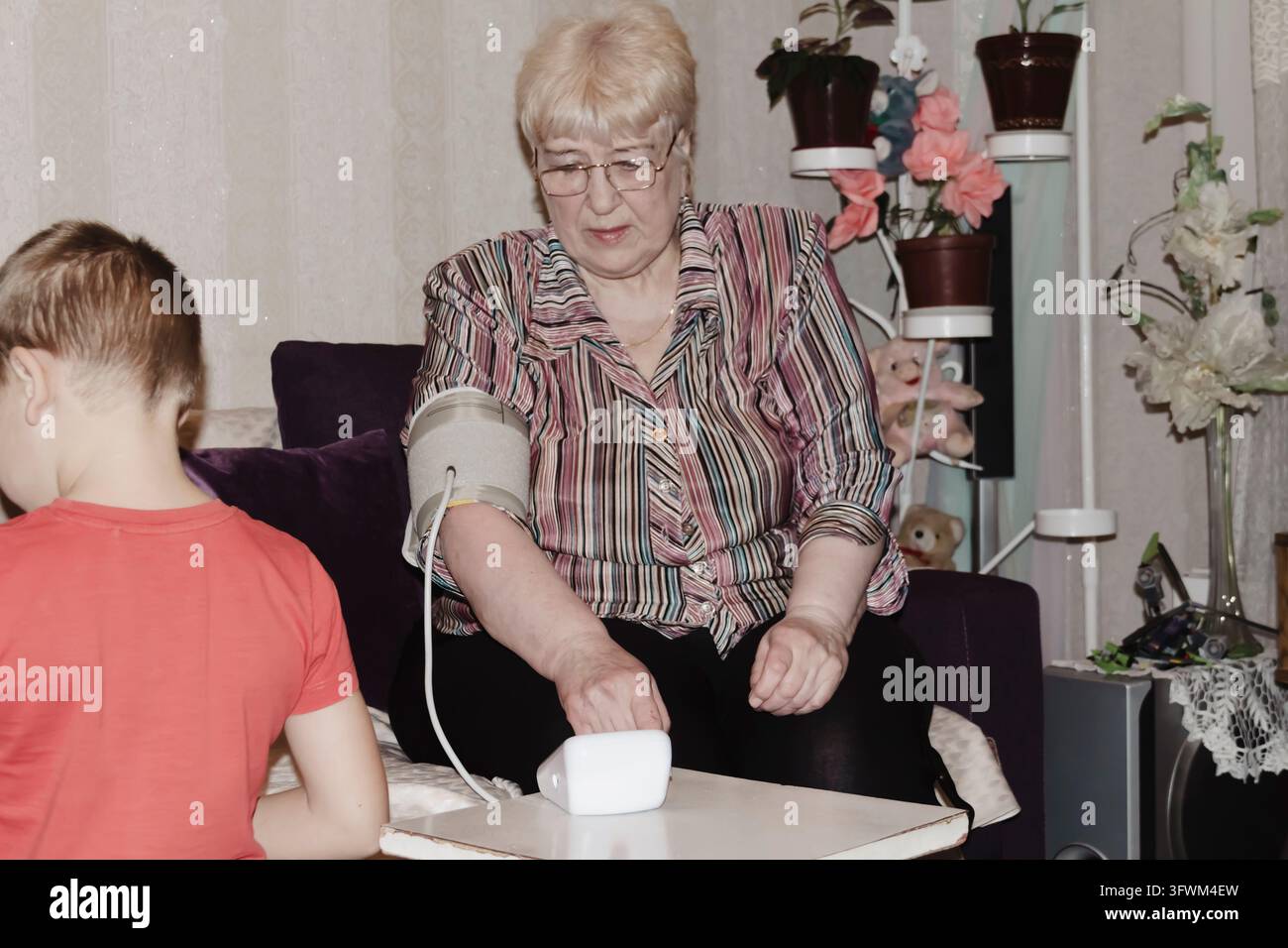 An elderly woman with hypertension measures her own blood pressure at ...