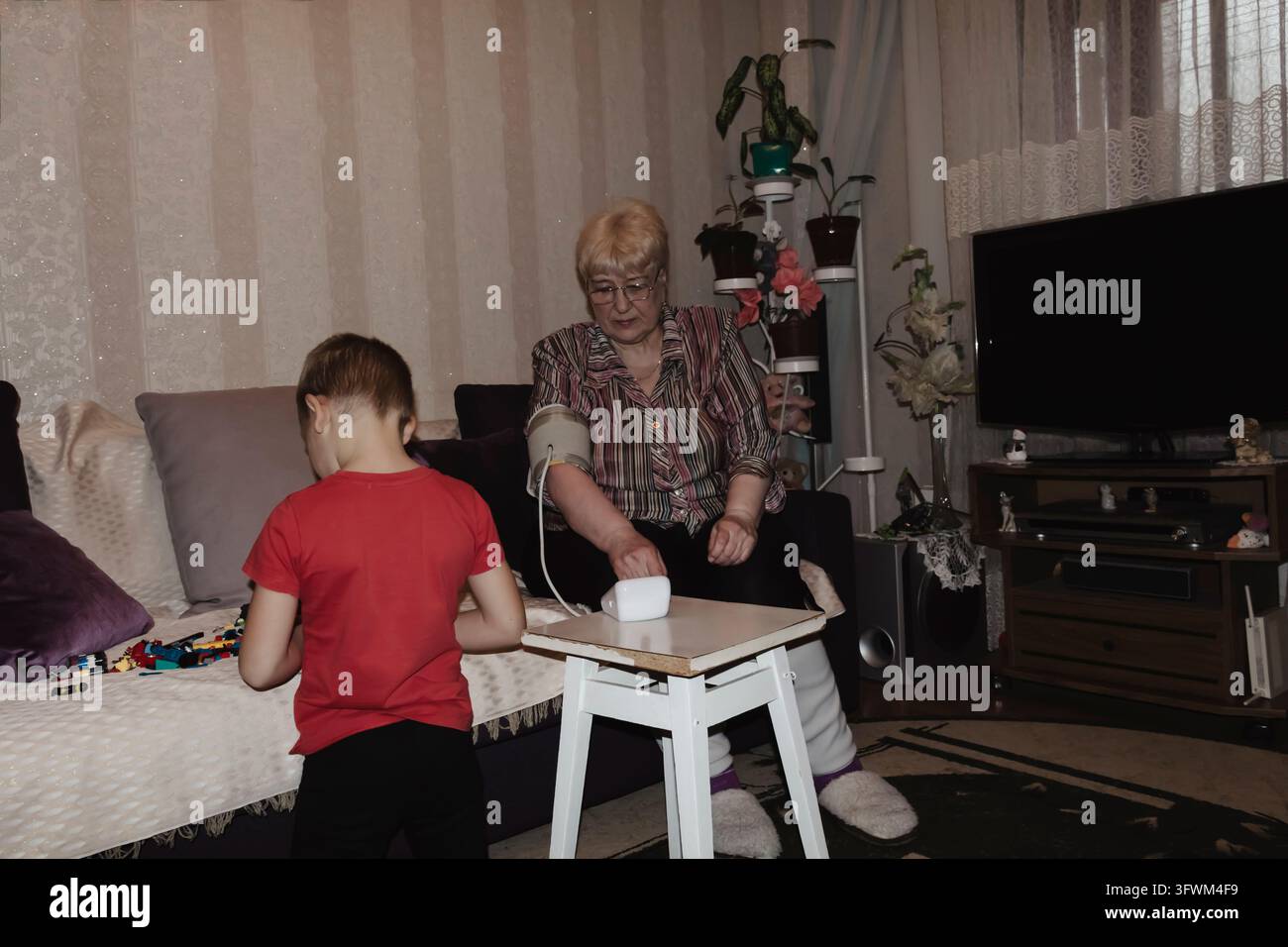 An elderly woman with hypertension measures her own blood pressure at ...