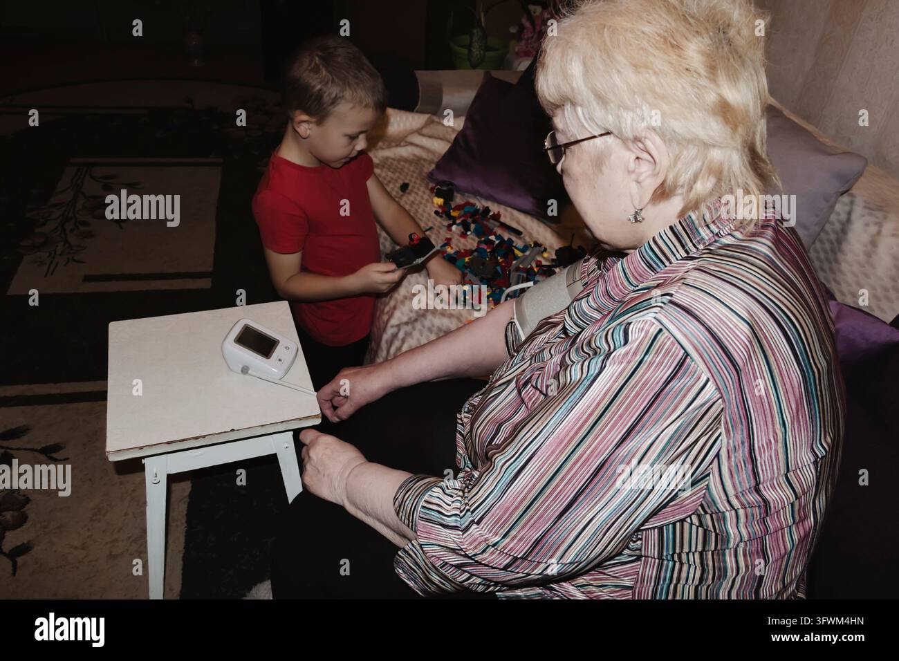 An elderly woman with hypertension measures her own blood pressure at ...