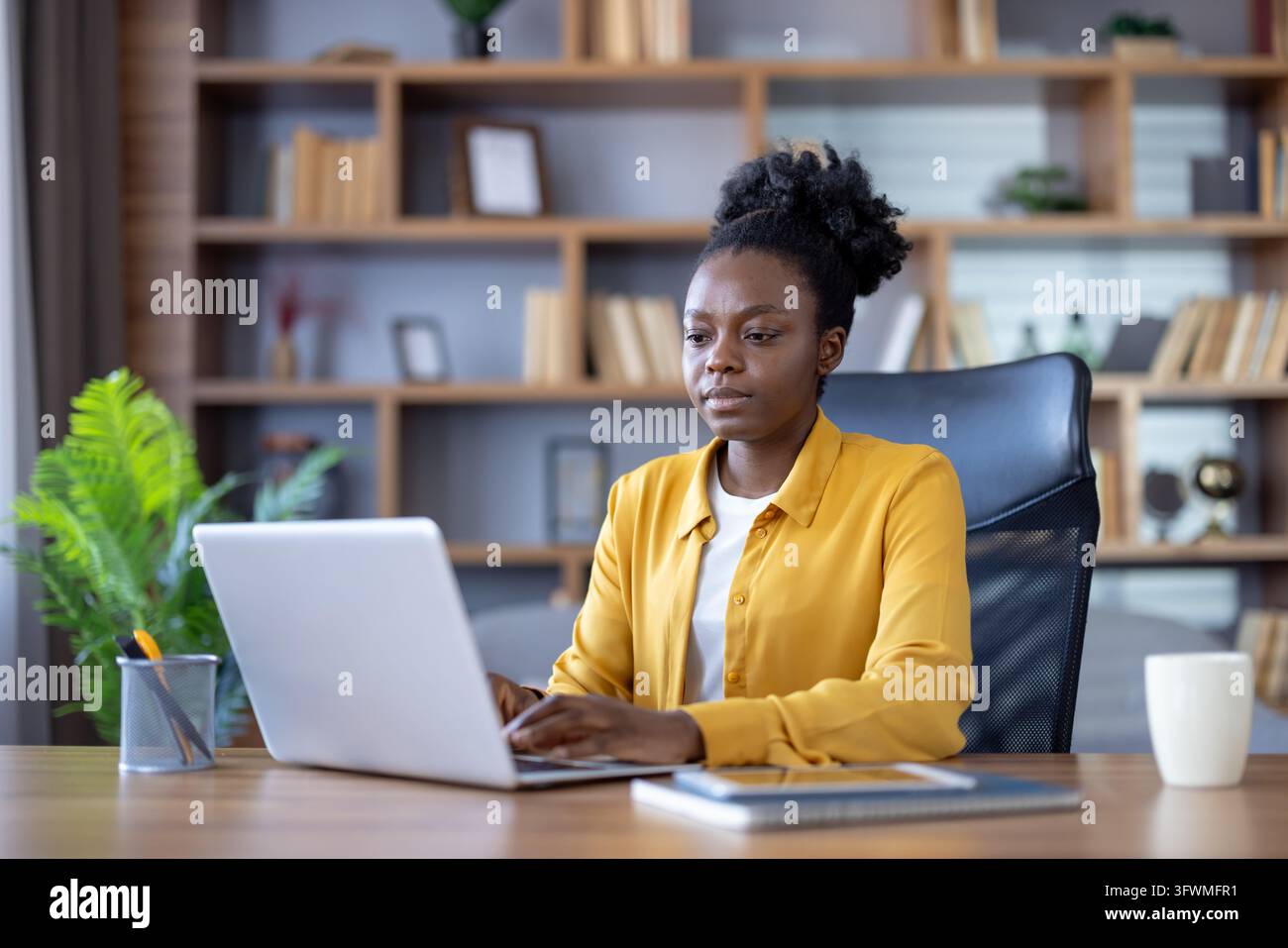 Young professional woman works on laptop at modern office desk, focused ...