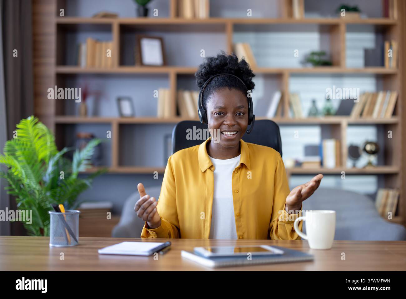 Confident woman with headset sits at home office desk, smiling during ...