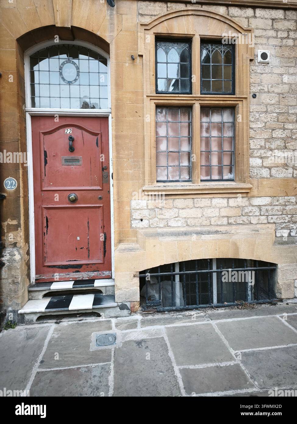 Red front door with a leaded fanlight beside a stone mullioned window ...