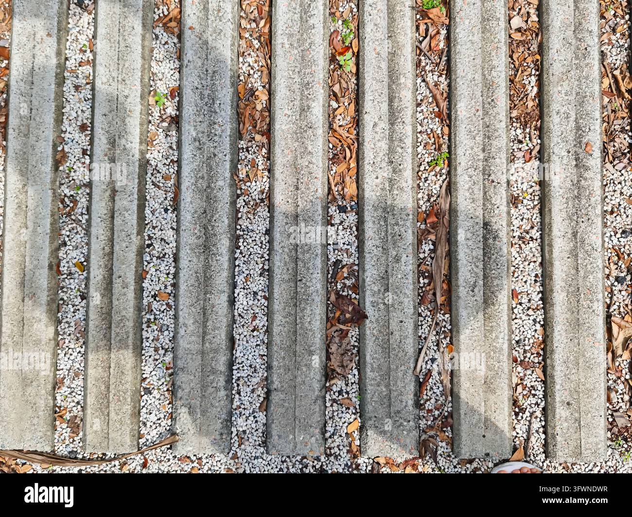 Concrete strips display a pattern on ground covered with small stones ...