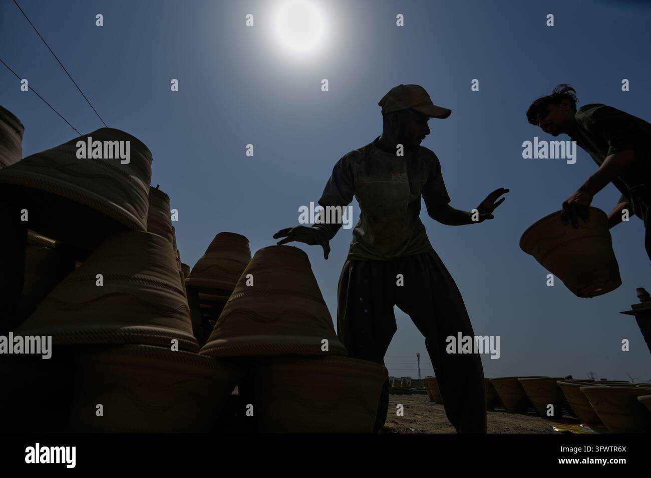 Workers arrange pots at a clay factory on a hot day in Karachi ...