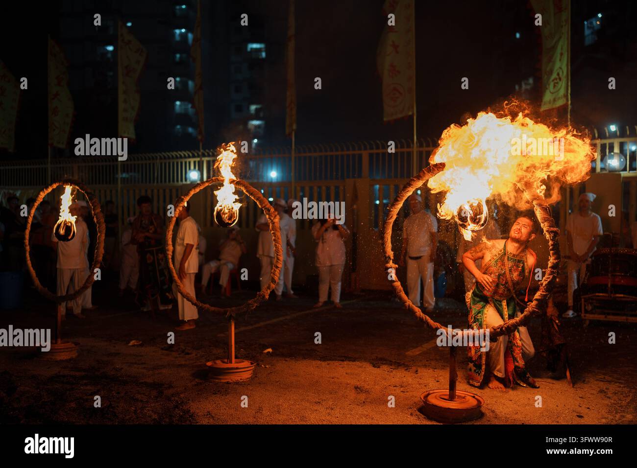 A devotee breathes fire through a hoop during the Nine Emperor Gods ...
