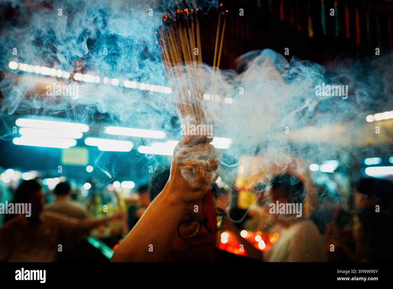 A devotee holds burning incense sticks while praying at the Nine ...