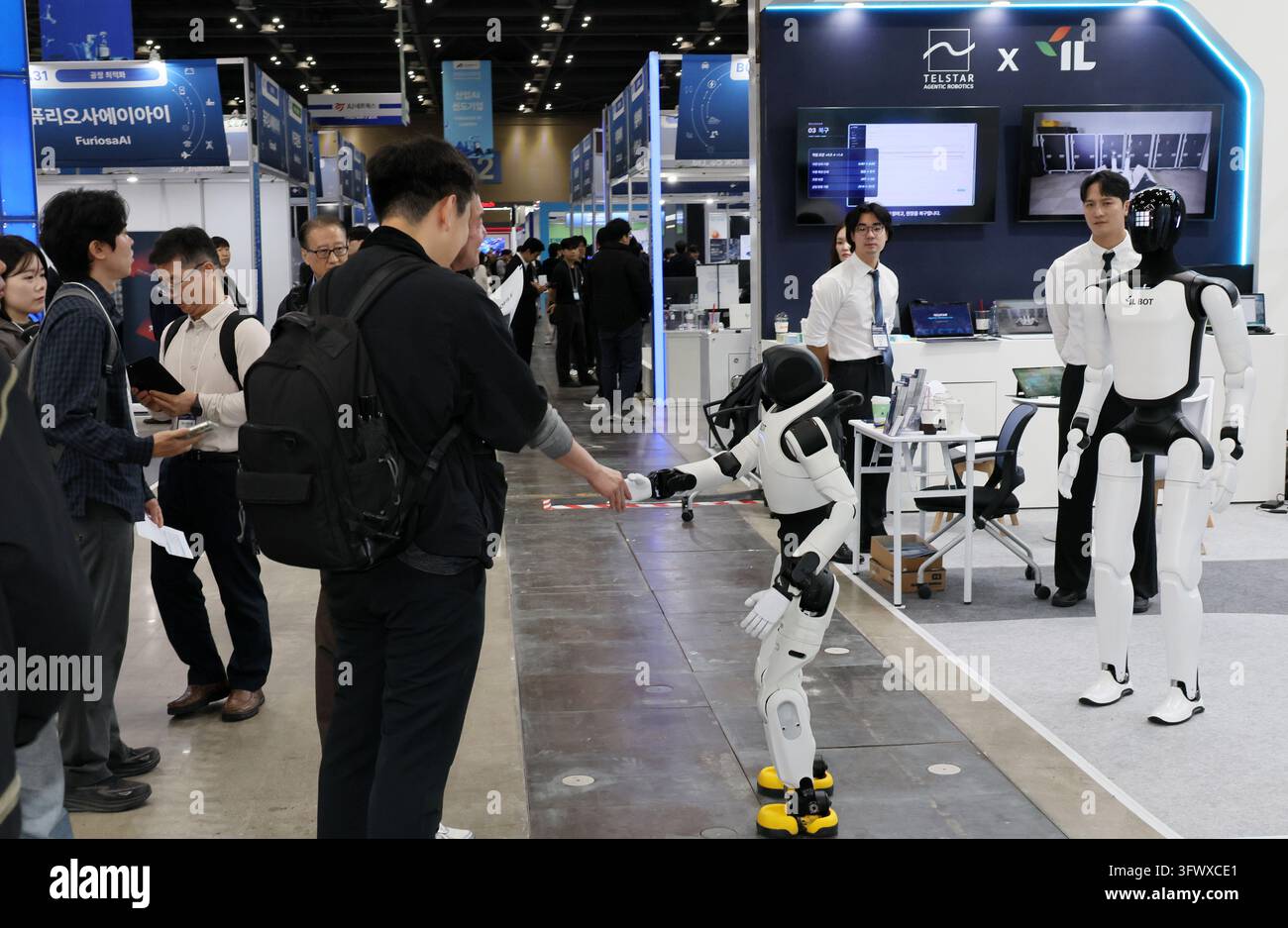 21st Oct, 2026. Industrial AI Expo A humanoid robot shakes hands with a ...