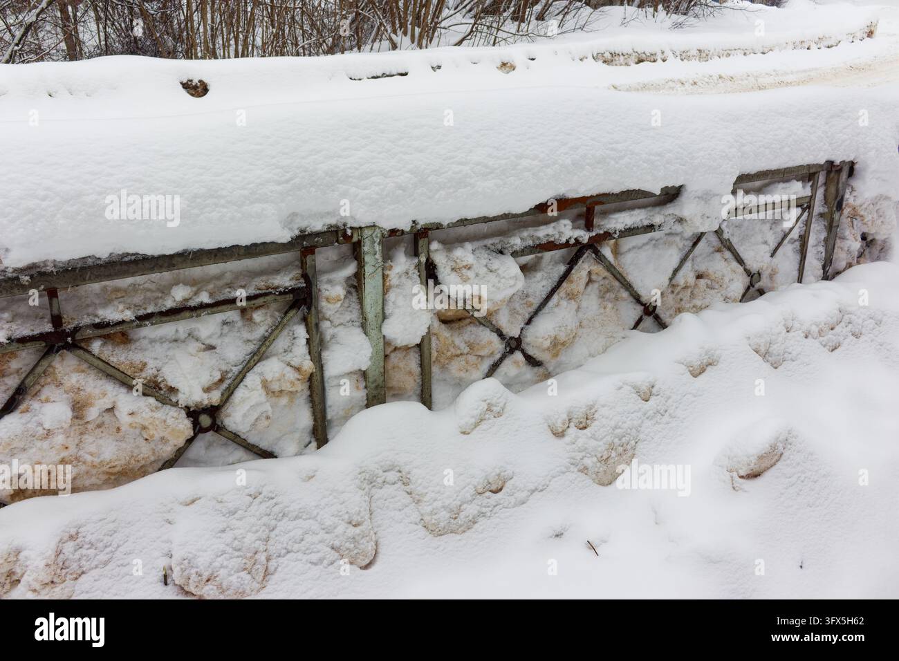 Metal fence section completely buried under heavy mounds of dirty snow ...
