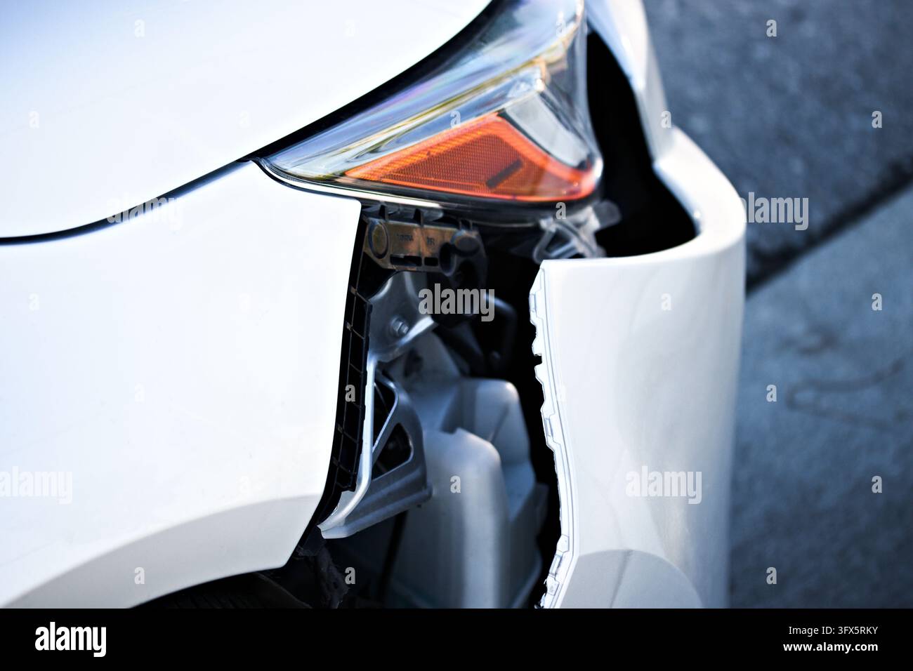 Close-up photograph of a white car with a damaged front bumper ...