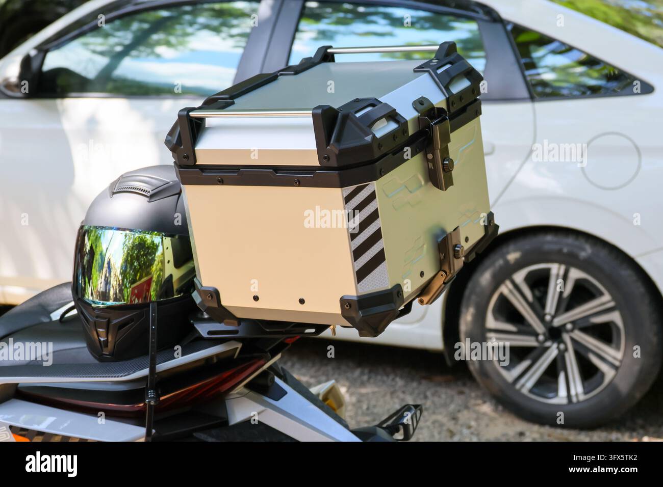 An adventure motorcycle cargo case and helmet beside white crossover ...
