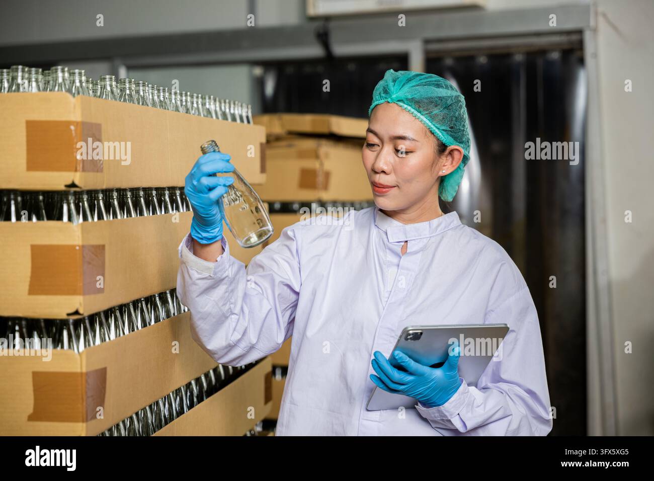 At the beverage factory a diligent QC woman uses a digital tablet to ...